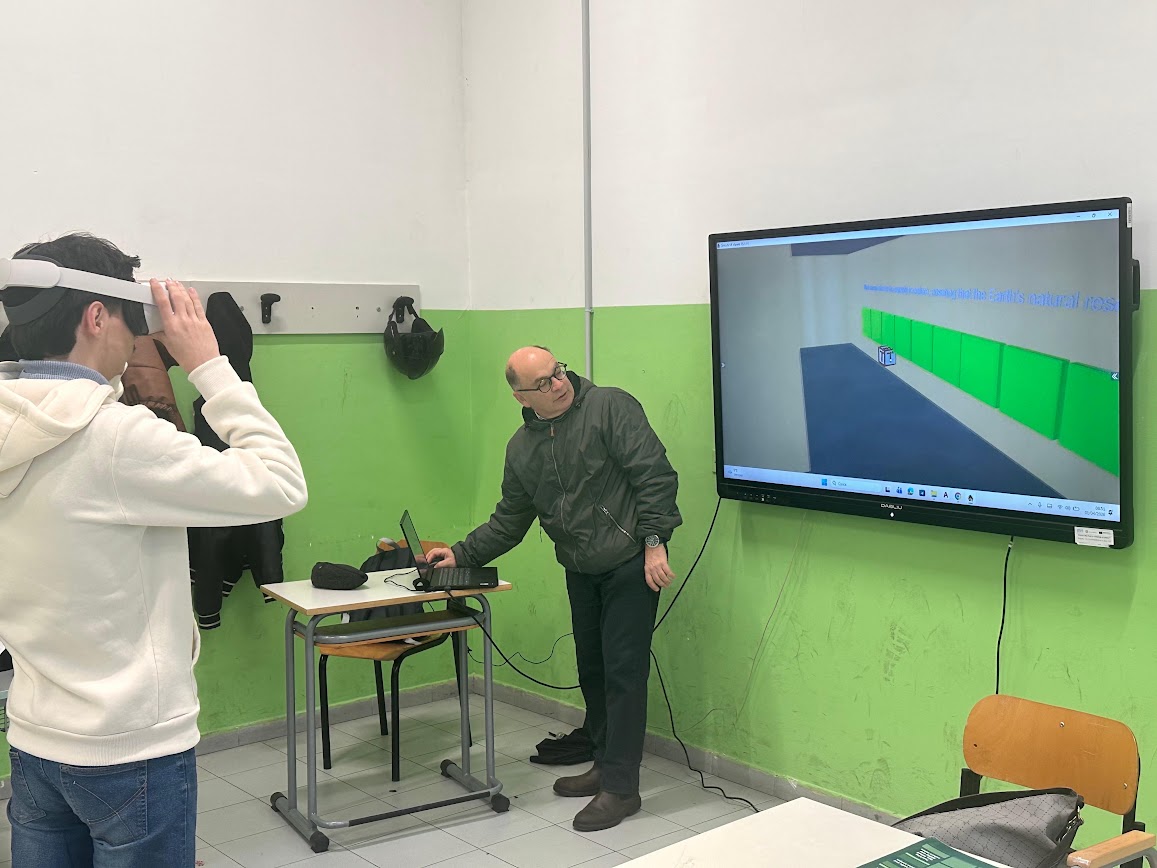 Student putting on a VR headset as a teacher sets up the VR learning activity on a laptop and classroom screen in Naples