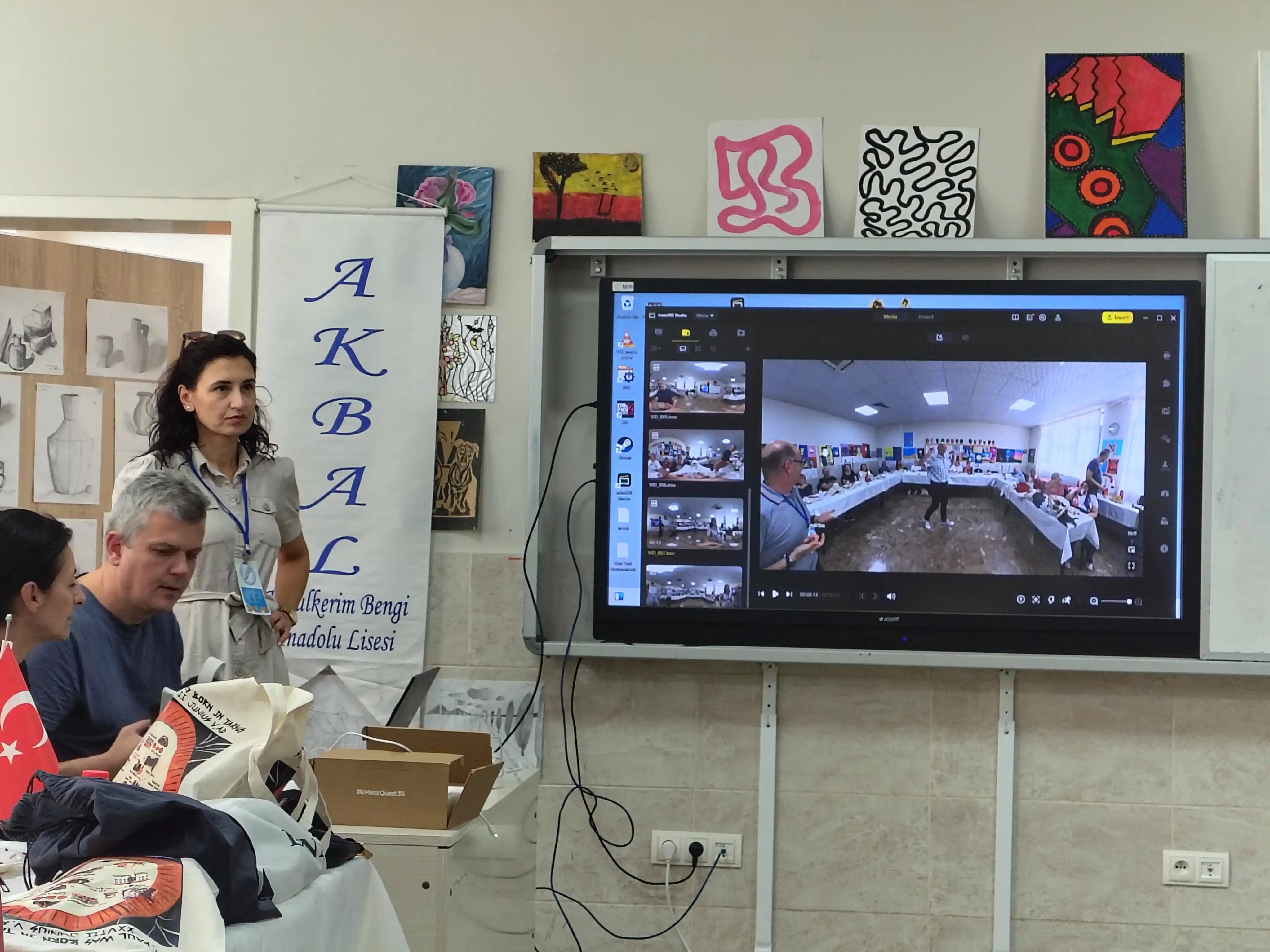 Participants beside an interactive screen displaying 360-degree video, with a VR headset box on the table, during the second Community & English training in Tarsus/Mersin