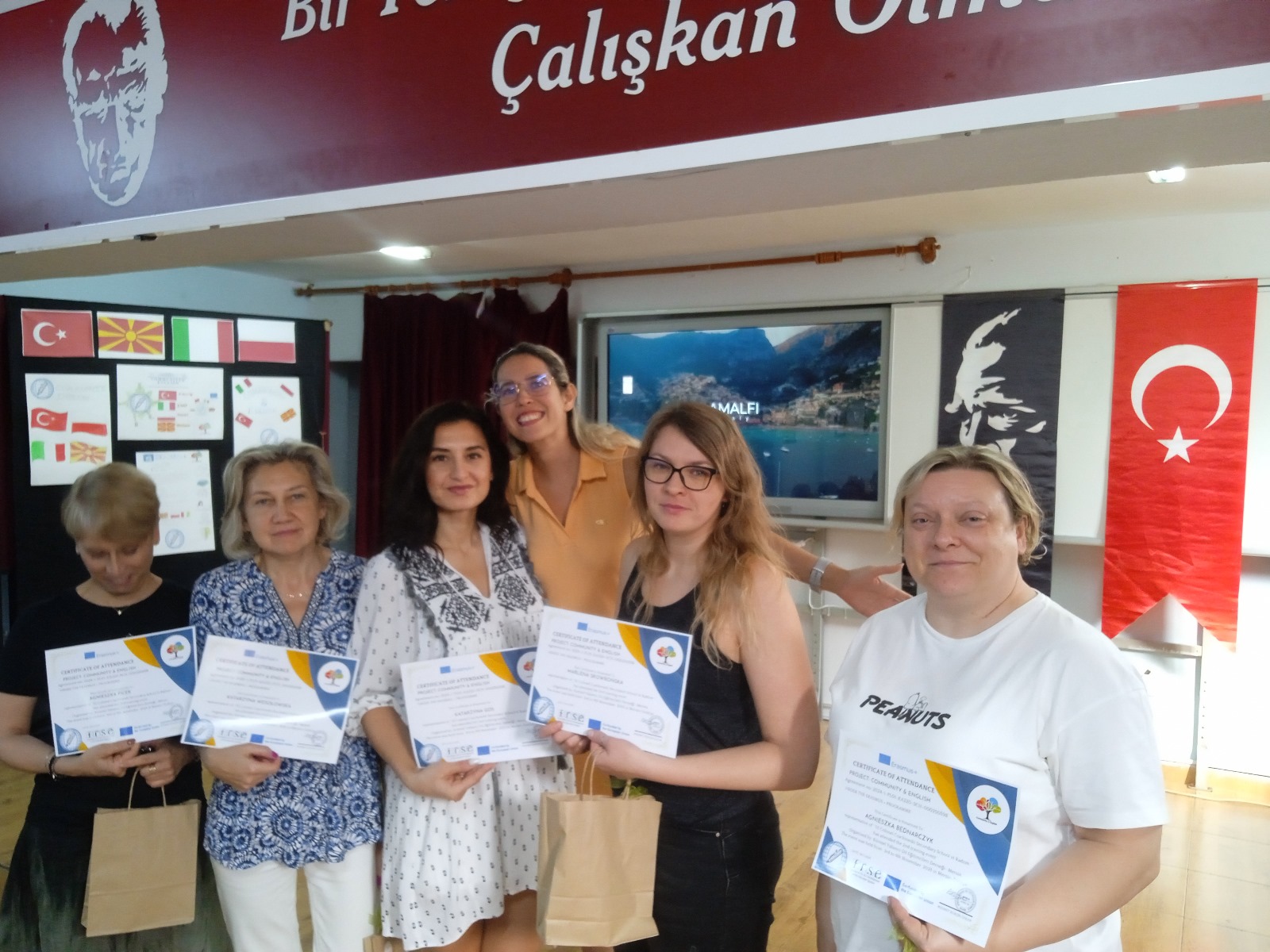 Teachers presenting their Community & English certificates of attendance in front of partner country flags in Tarsus/Mersin